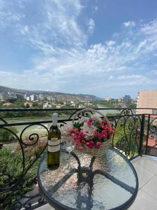 a glass table with a bottle of wine and a basket of flowers at Hotel Rich in Tbilisi City