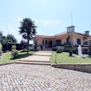 une maison avec un palmier et une allée en briques dans l'établissement Casa Além Rio - quartos para 6 hóspedes em Santo Tirso, à Santo Tirso
