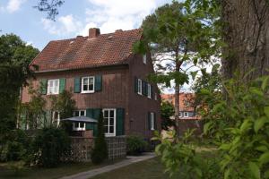 una casa de ladrillo con un paraguas delante de ella en Ferienhaus Haas - Am Heidschnuckenweg en Faßberg