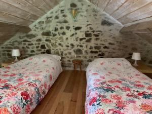 a bedroom with two beds and a stone wall at Petite maison Conjat in Saint-Julien-le-Petit