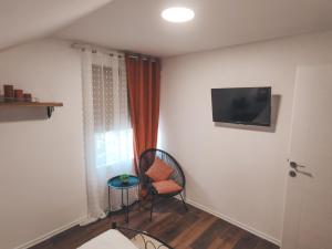 a room with two chairs and a television on a wall at Villa-Apartments Bognar in Velika