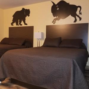 Frontier Lodge في لاندر: غرفة نوم مع سرير مع اثنين من الثيران على الحائط