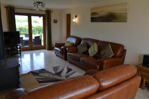 a living room with brown leather couches and a television at Mutton Barn in Alcester