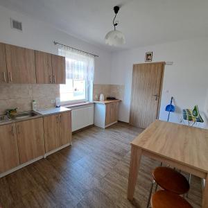 a kitchen with wooden cabinets and a table and a window at Pokoje u Teresy in Rewa