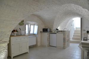 una cucina con armadi bianchi e un muro in pietra di Attico Cinquantasei a Cisternino