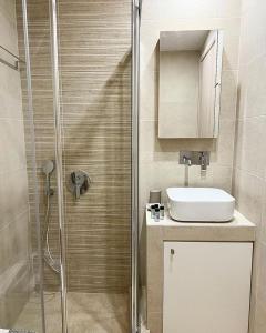La salle de bains est pourvue d'une douche et d'un lavabo. dans l'établissement "Calm Joy & J" - Family, à Ermoúpoli