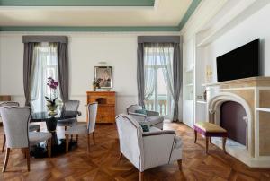 a living room with a fireplace and a table and chairs at Grand Hotel Des Etrangers in Siracusa