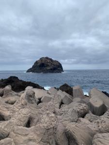een berg rotsen op een strand met een eiland in de oceaan bij EL CALETON, GARACHICO in Garachico