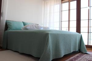 a bedroom with a bed with a green blanket and windows at Nalyakonak in Alacati