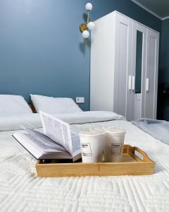 - un plateau avec des livres et 2 tasses de café sur le lit dans l'établissement Апартаменты у Триумфальной арки, à Astana