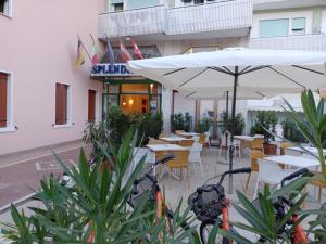 un restaurante con mesas, sillas y sombrilla en Hotel Splendid, en Caorle