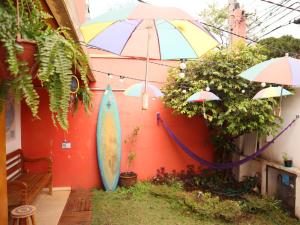 ein Haus mit einem Regenschirm und einem Surfbrett an der Wand in der Unterkunft MADÁ hostel in São Paulo