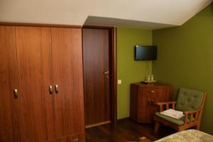a bedroom with a bed and a chair and a television at Pensiunea Clasic Hunedoara in Peştişu Mare