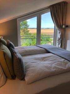 - une chambre avec un grand lit et une grande fenêtre dans l'établissement Gästehaus Muhl, à Strukkamp auf Fehmarn