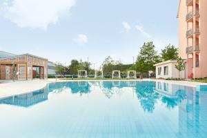 a swimming pool with blue water in front of a building at Hotel Europa Fit Hévíz in Hévíz