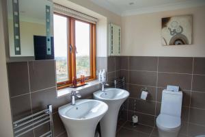 uma casa de banho com 2 lavatórios, um WC e uma janela em Mutton Barn em Alcester