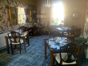 uma sala de jantar com mesas e cadeiras e um espelho em CornerHouse Guesthouse em Penrith