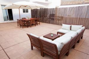 une terrasse avec un canapé, des tables et un parasol dans l'établissement Apartamento con gran terraza Chill Out, à Guía de Isora