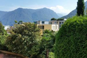 a building with trees and mountains in the background at LOFT 18! Cozy loft downtown near the lake with FREE PARKING in Lugano
