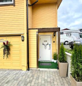 Una casa amarilla con una puerta blanca con un ciervo. en Guesthouse in Tromso center by Dada en Tromsø