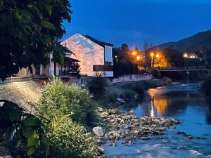 a river at night with a building and a bridge at Motel Platani Kotor Varoš in Kotorište