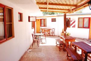 une terrasse avec des tables et des chaises en bois, une table et des bancs dans l'établissement Hostal Miskanty, à San Pedro de Atacama