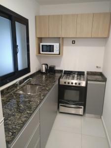 a kitchen with a stove and a sink and a microwave at DPTO EN VILLA ALLENDE A ESTRENAR !! in Villa Allende