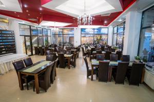 un comedor con mesas, sillas y ventanas en Hotel Prestige, en Mamaia