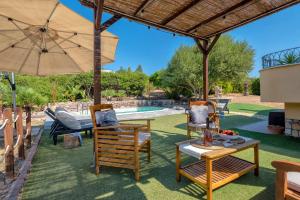 a patio with chairs and a table and an umbrella at Villa Pedra Alghero - appartamento in villa con piscina in Alghero