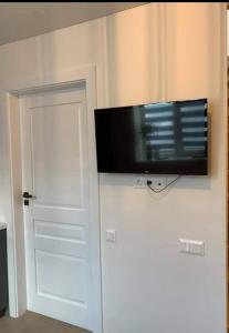 a flat screen tv on a wall next to a door at Eli Apartamentai in Juodkrantė +21 photos