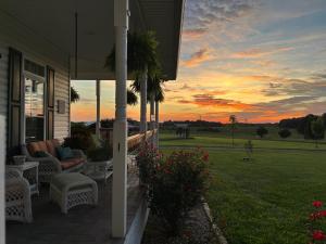 a porch of a house with a sunset in the background at Barren Breeze Bed and Breakfast in Lucas