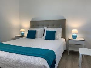 a bedroom with a large bed with blue and white pillows at Vilabranco in Albufeira