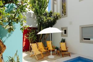 une terrasse avec une table, des chaises et un parasol dans l'établissement PTM DownTown Hostel&Suites, à Portimão