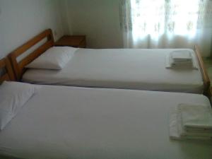 2 camas individuales en un dormitorio con ventana en La Cite Family Hotel & Apartments en Moraitika