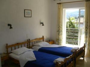 two beds in a bedroom with a large window at La Cite Family Hotel & Apartments in Moraitika