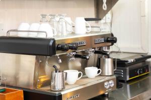 a coffee machine with cups on a counter in a kitchen at Rock Hyrax Hotel in Nakuru