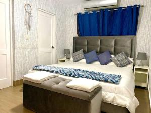 1 dormitorio con 1 cama grande y cortinas azules en Casa con Parqueo Privado, Patio y Jacuzzi., en Santo Domingo