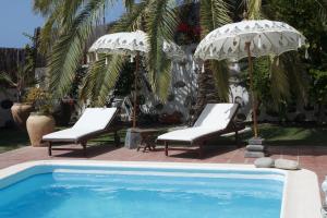 a pool with two chairs and two umbrellas at Villas Parque Mirador in Playa de Santiago