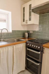 a kitchen with a stove and a sink at Lovely, Cosy Beachside Cottage 1 - Perfect Location in Llandudno