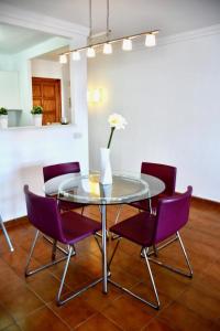 une table en verre avec des chaises violettes et un vase avec une fleur dans l'établissement Meerblick Apartment Sabina, à Cala Millor