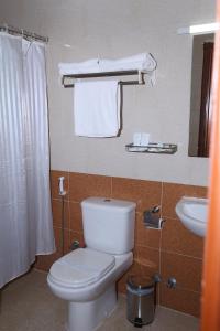 a bathroom with a toilet and a sink with towels at Jarzez Hotel Apartments Al Hail in Seeb