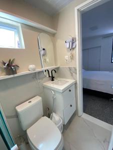 a bathroom with a toilet and a sink and a mirror at Apartamento Atlântico in Fortaleza