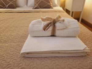 una pila de toallas con un arco en la cama en La Perla Di Noto, en Noto
