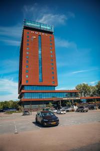 un grand bâtiment avec une voiture garée dans un parking dans l'établissement Van der Valk Hotel Schiedam, à Schiedam