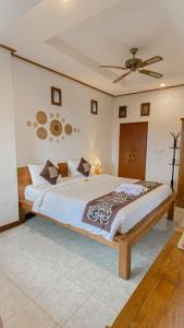 a bedroom with a large bed with a ceiling fan at Raditya House in Ubud