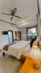 a bedroom with a large bed with a ceiling fan at Raditya House in Ubud