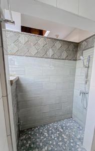 La salle de bains est pourvue d'une douche et d'un mur carrelé. dans l'établissement Raditya House, à Ubud