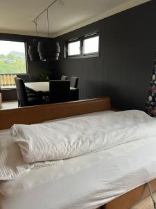 1 dormitorio con 1 cama blanca, mesa y sillas en Feriehus i Flekkefjord med panoramautsikt en Flekkefjord