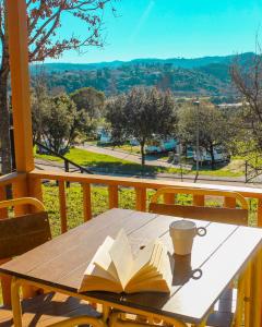 una mesa de madera con un libro y una taza de café. en Coimbra Camping & Bungalows, en Coímbra