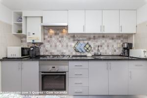 a white kitchen with white cabinets and appliances at Akisol Lagos Beach in Burgau